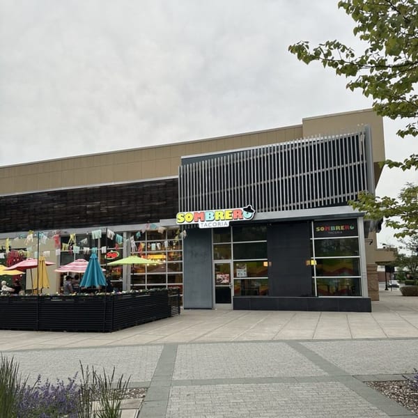 Exterior of Sombrero Tacoria with colorful umbrellas on the patio and a modern facade.