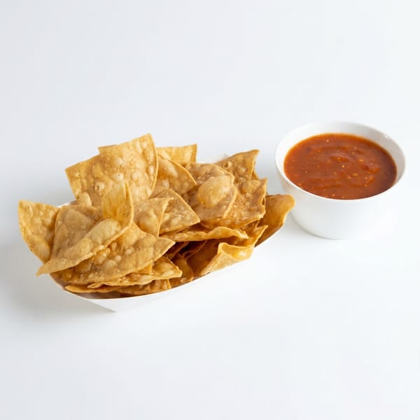 Crispy tortilla chips in a white boat with a side of red salsa in a white bowl.