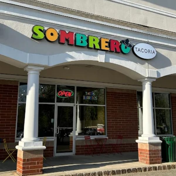 Exterior view of Sombrero Tacoria restaurant with colorful signage, brick facade, and outdoor seating.