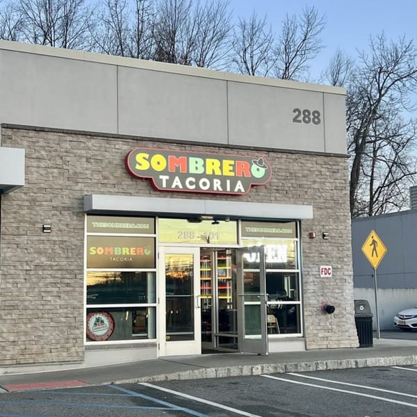 Exterior of Sombrero Tacoria restaurant with a colorful sign, stone facade, and glass doors.