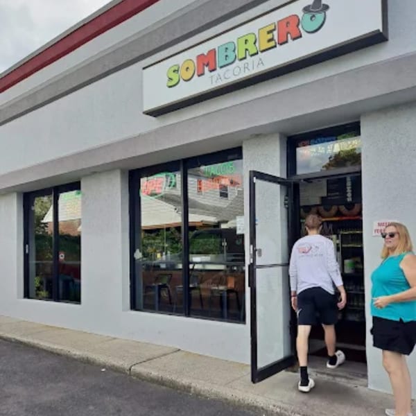 The exterior of Sombrero Tacoria, with a man entering and a woman standing nearby.
