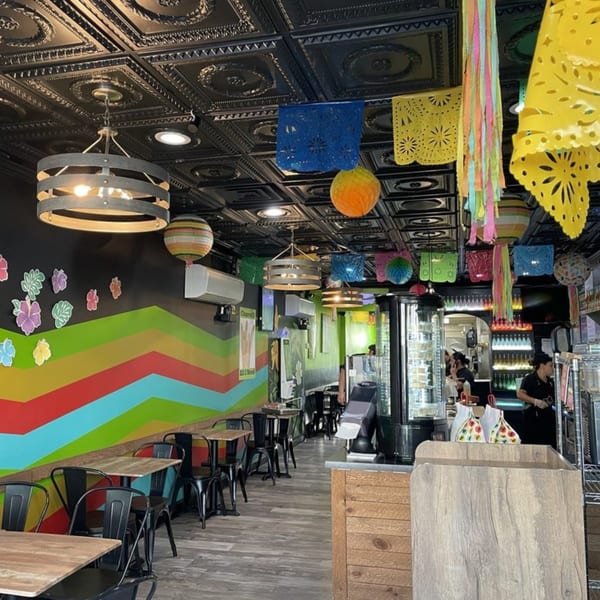 Colorful restaurant interior with patterned ceiling, festive decorations, and tables with black chairs.