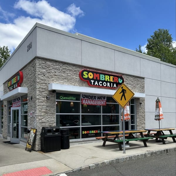 Exterior of Sombrero Tacoria with stone facade, large windows, and outdoor picnic tables.